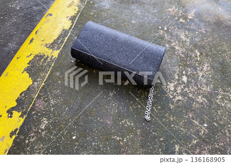 lost black glitter clutch purse with silver chain and rhinestone detail abandoned on a wet concrete ground next to a yellow painted curb lost black glitter clutch purse with silver chain and rhinestone detail abandoned on a wet concrete ground next to a yellow painted curb 136168905