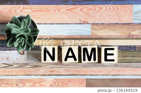 The name symbol. The concept word is the name on the wooden blocks. Beautiful table background. The name symbol. The concept word is the name on the wooden blocks. Beautiful table background. 136169329