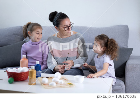 Mother and two daughters painting Easter eggs at home Mother and two daughters painting Easter eggs at home 136170638