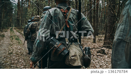 Wehrmacht squad marching in single file through forest during WWII patrol 136170784