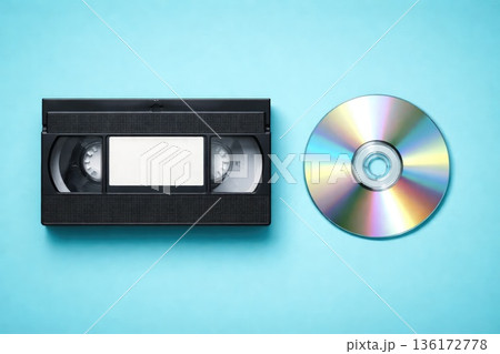 VHS Cassette Tape and Compact Disc on Blue Background Retro and Modern Media VHS Cassette Tape and Compact Disc on Blue Background Retro and Modern Media 136172778