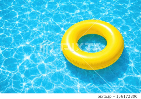 Bright yellow inflatable swim ring floating in clear blue swimming pool water 136172800