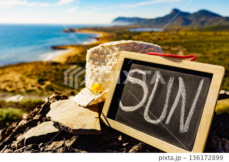 Black board with word sun against sea coast Black board with word sun against sea coast 136172899