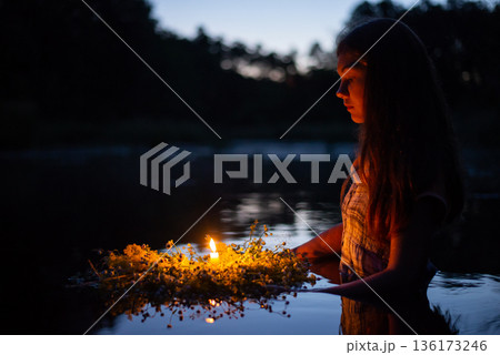 Portrait of a small girl in river late at night, set the wreath to float with a candle. Ivan Kupala tradition in Ukraine 136173246