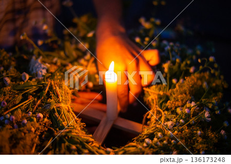 Close-up shot of a kupala wreath in girl`s hands on the river. Floating ritual wreath on the river with a candle, Ivan kupala celebration 136173248