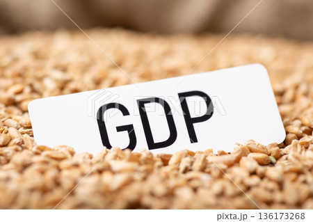 Paper with inscription GDP on wheat grain. Dependance of GDP of country on harvest of wheat concept Paper with inscription GDP on wheat grain. Dependance of GDP of country on harvest of wheat concept 136173268