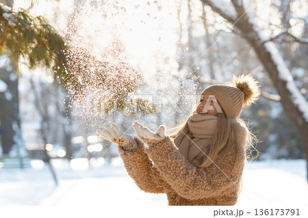 Happy female plays with snow in sunny winter day Happy female plays with snow in sunny winter day 136173791