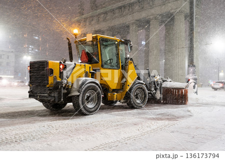 Winter service vehicles. Big yellow snow plow tractor working in city at night in heavy snowfall 136173794