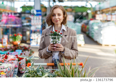 Woman with shopping trolley choosing floral plants for home 136173796
