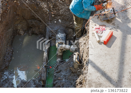 Utility worker fixing broken water main, top view Utility worker fixing broken water main, top view 136173822