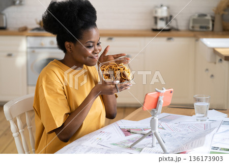 Black woman food blogger record video eat pasta at kitchen or call friends or family with smartphone Black woman food blogger record video eat pasta at kitchen or call friends or family with smartphone 136173903
