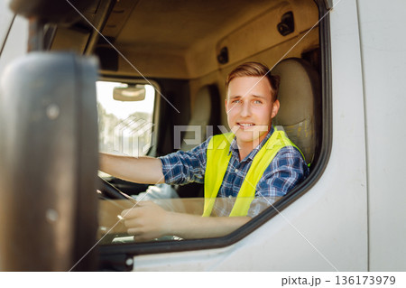 Driver at the wheel of a truck at work. Driver or forwarder on truck on a transshipment point Driver at the wheel of a truck at work. Driver or forwarder on truck on a transshipment point 136173979
