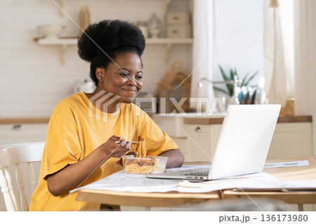 African female eat and watch video or webinar on laptop or make conference call to friends on break 136173980