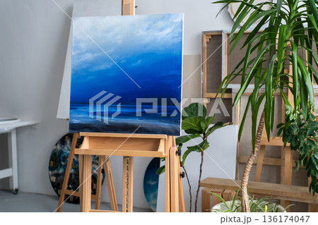 Art studio workshop space in loft apartment, easel displaying finished creative artwork on canvas. Art studio workshop space in loft apartment, easel displaying finished creative artwork on canvas. 136174047
