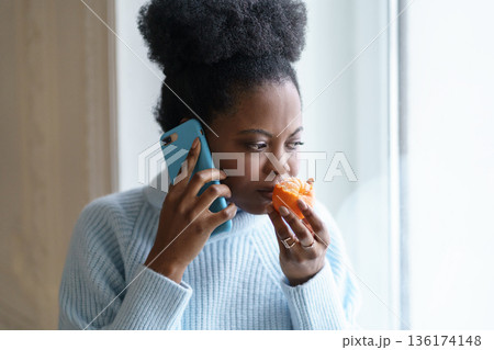 Sick Black woman trying to sense smell of half fresh tangerine orange talking on phone. Covid-19 Sick Black woman trying to sense smell of half fresh tangerine orange talking on phone. Covid-19 136174148