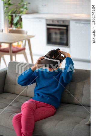 Young woman puts on VR glasses for first time and prepares to play interesting games at home 136174184