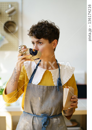 Female ceramist drink coffee and eat snack in art studio at break from master class produce pottery 136174216
