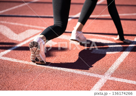 Rear view of woman jogger on running track getting ready to start run.. Rear view of woman jogger on running track getting ready to start run.. 136174266