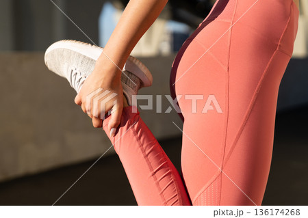 Close up of sporty female stretching leg muscles before run. Jogging, workout and fitness concept 136174268