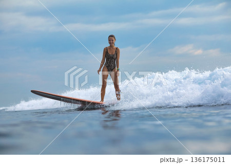 Lady At Sunrise Maintains Poise On Her Surfboard Surrounded By Surf And Spray 136175011