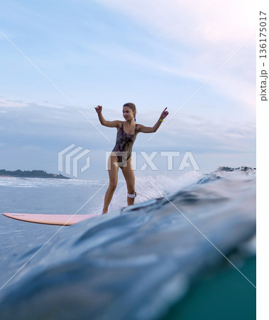 Lady At Sunrise Maintains Poise On Her Surfboard Surrounded By Surf And Spray 136175017