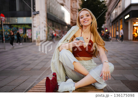 Young woman smiling, sitting on bench in Vienna, Austria Young woman smiling, sitting on bench in Vienna, Austria 136175098