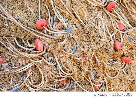 Detailed close view of brown fishing nets with red floats for marine industry and texture use. 136175300