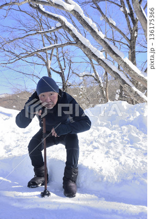 雪道で杖を使ってリハビリをしている老人 136175366