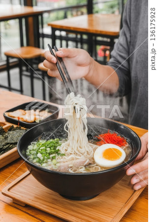 Person lifting ramen noodles with chopsticks Person lifting ramen noodles with chopsticks 136175928