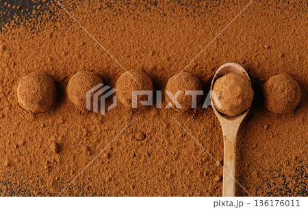 Cocoa dusted chocolate truffles in a row with wooden spoon, top view Cocoa dusted chocolate truffles in a row with wooden spoon, top view 136176011