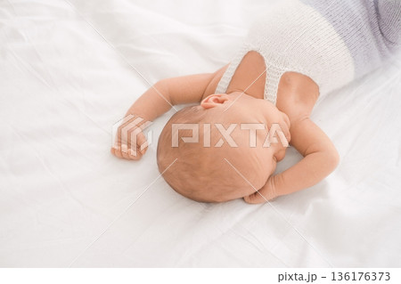 Peaceful sleeping newborn baby on white bed, symbol of childhood, care, safety, and International Childrens Day. 136176373