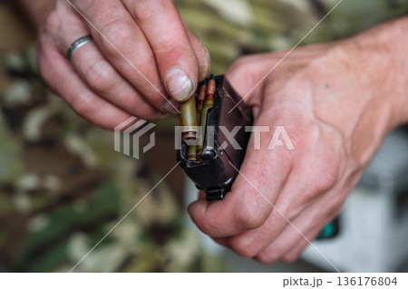 Loading rifle magazine with ammunition close up 136176804