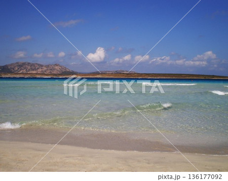 The breathtaking sea of Stintino near Olbia, Sardinia, reveals crystal-clear turquoise waters gently washing over fine white sand. Bathed in warm Mediterranean sunlight, this peaceful coastal 136177092