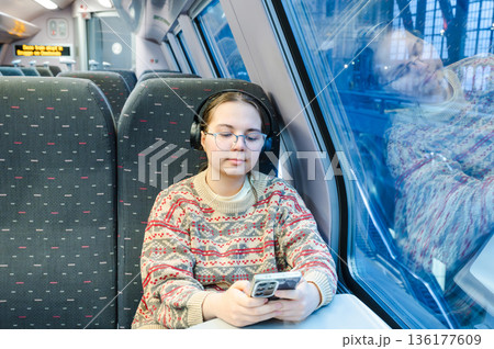 Smiling teenager girl with gallses and headphones in train 136177609