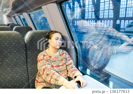 Smiling teenager girl with gallses and headphones in train 136177615