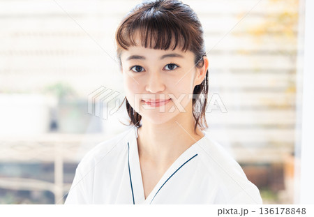 スクラブを着て窓辺に立つ医療従事者の女性 スクラブを着て窓辺に立つ医療従事者の女性 136178848