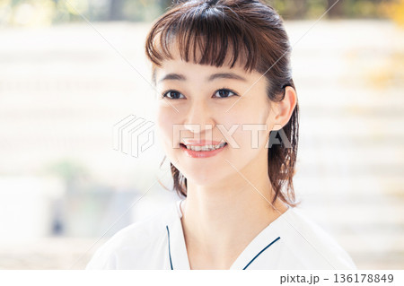 スクラブを着て窓辺に立つ医療従事者の女性 136178849