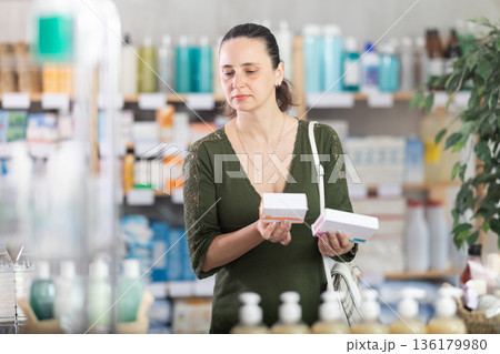 woman chooses packages of pills in a pharmacy 136179980