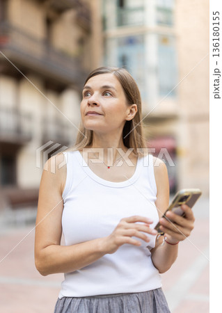 Female pedestrian with phone in summer European capital 136180155