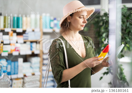 Woman buyer select sunscreen cream 136180161