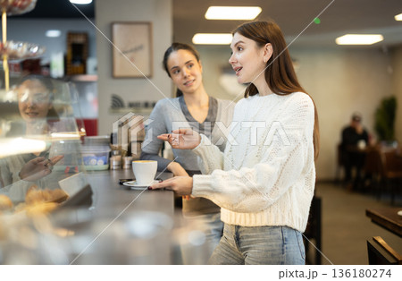 Two women talking and drinking coffee in cafe 136180274
