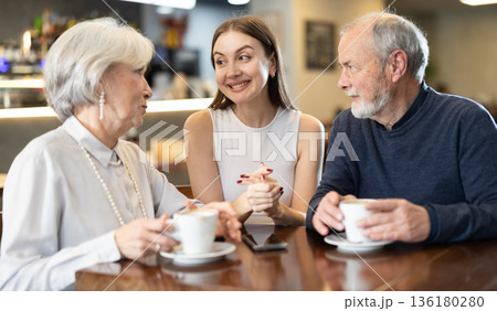 Senior couple and girl sitting at table, talking, laughing, joking, chatting 136180280