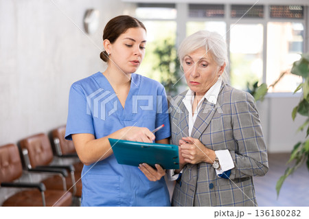 Attentive female doctor prescribing tests to patient of clinic to check state of health Attentive female doctor prescribing tests to patient of clinic to check state of health 136180282