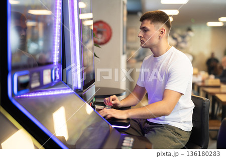 guy plays a slot machine with video games guy plays a slot machine with video games 136180283