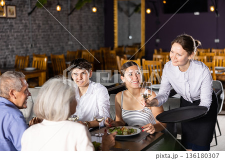 Waitress serving wine to guests of different ages in restaurant Waitress serving wine to guests of different ages in restaurant 136180307