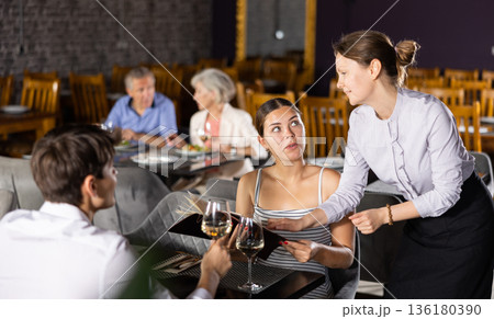 Woman waiter takes order from young couple in restaurant 136180390