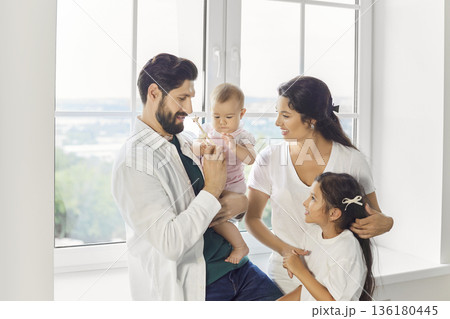 Happy mother, father and kids sharing playful family moments together by the window at home  136180445
