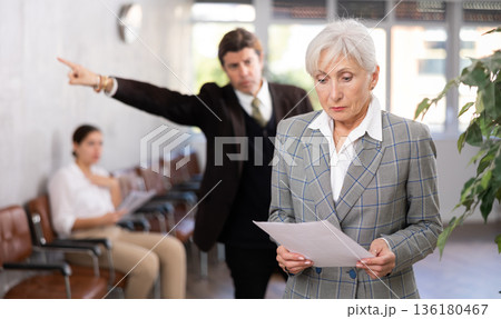 Businessman yelling at mature woman manager in office Businessman yelling at mature woman manager in office 136180467
