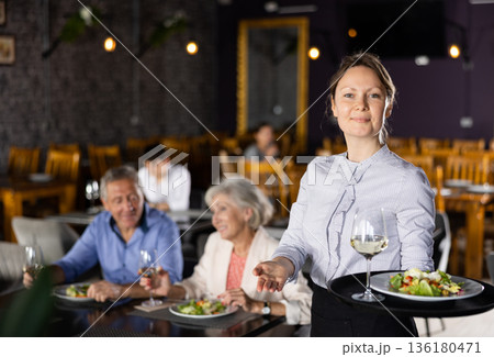 Smiling female owner of restaurant standing with serving tray 136180471