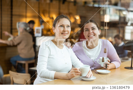 Carefree female colleagues drinking coffee and chatting in cafe 136180479